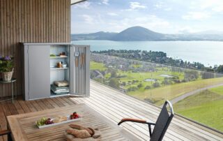 Terrassenbox Balkonbox auf Holzterrasse mit Ausblick auf einen See.